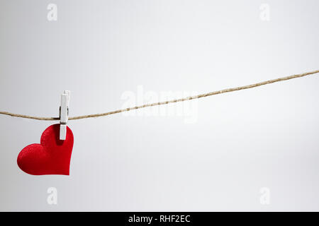 Single einsam Rotes Herz hängen von String von wäscheklammer auf weißem Hintergrund. Der Valentinstag mit Kopie Raum Stockfoto