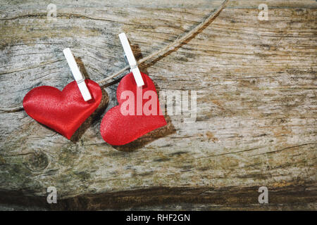 Zwei adorable roten Herzen auf String mit Wäscheklammern auf Holz- Hintergrund. Der Valentinstag Szene mit Kopie Raum Stockfoto