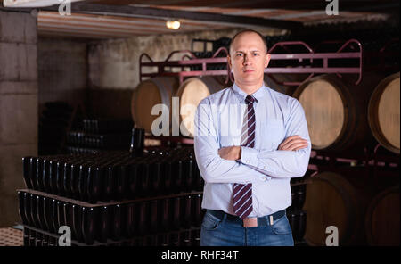 Sicher froh, heiter erfolgreiche Mann Winzer im eigenen Weingut vault Posing Stockfoto