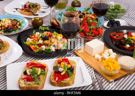Ansicht von oben viele Platten mit verschiedenen vegetarisches Essen und ein Glas Wein Stockfoto
