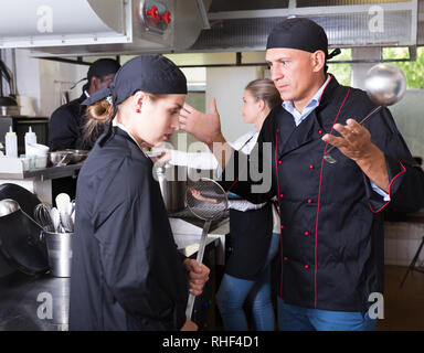 Wütend männlichen Chef mit seinem weiblichen Assistant in der gewerblichen Küche Stockfoto