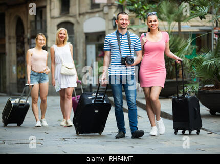 Portrait der glücklichen Familie, die zu Fuß und ziehen Gepäcktaschen in der Stadt im Sommer Tag Stockfoto