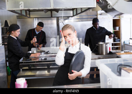 Unglücklich und müde junge Kellnerin warten bestellten Gerichte im Restaurant Küche Stockfoto