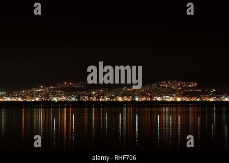 Panorama mit leuchtenden Lichtern des Hafens die Stadt Izmir bei Nacht, Türkei. Stockfoto