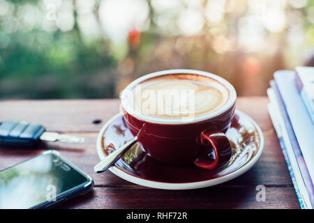 Tasse heißen Kaffee, Bücher, Smartphone und Tasten auf der Holzplatte Stockfoto