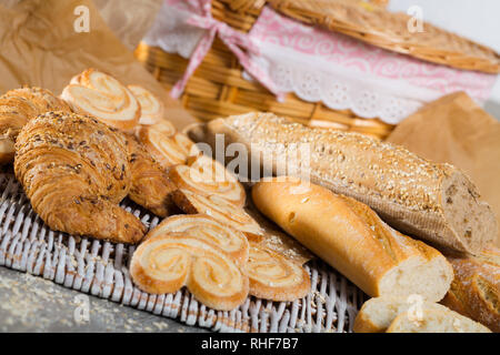 Sortiment an frischen Backwaren auf wicker Mat mit Korb auf hölzernen Hintergrund Stockfoto