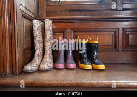 Drei Paar Gummistiefel - einen Erwachsenen und zwei Kinder - in eine Veranda eines Hauses Stockfoto