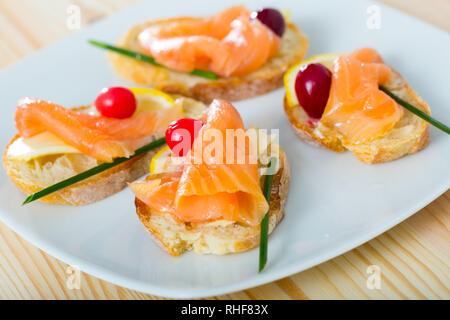 Tapas mit Lachsfarbenen mit Zitronenscheibe, Cranberry und Schnittlauch Stockfoto