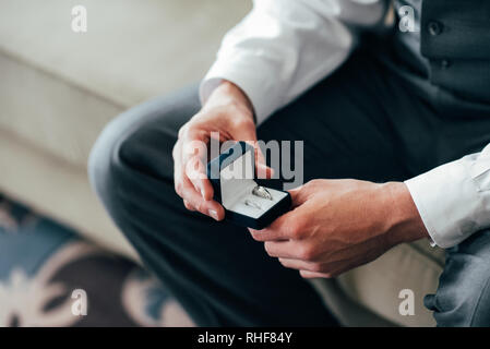 Bräutigam holding Trauringe auf die Palme, der Bräutigam in einem grauen Anzug, Bräutigam, Hochzeit Ringe, des Bräutigams hand mit einem Ring, Hochzeit Ring in Bräutigam han Stockfoto