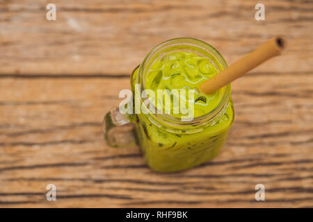 Grüner Tee Latte mit Eis in Mason jar und Stroh auf Holz- Hintergrund. Hausgemachte Eistee Matcha Latte Tee mit Milch null Abfall Stockfoto