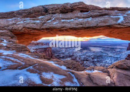 Die Wintersonne in den Wolken an einem kalten Januar morgen am Mesa Arch im Canyonlands National Park, Utah versteckt. (Panorama) Stockfoto
