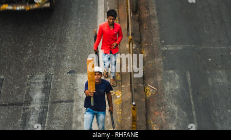 Youn Kerle, überqueren Sie die Straße in Bombay mit einem Kricket beat in seiner Hand. Stockfoto