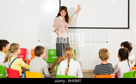 Junge Lehrerin am Whiteboard im Unterricht, die Durchführung von Unterricht mit Kindern Stockfoto