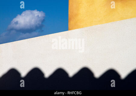 Zwei Außenwände des Hauses, Weiß und Gelb, ein kleines Stück blauen Himmel, wo eine kleine Wolke Fliegen gebunden. Unter dem bedrohlichen und schwarze Schatten von t Stockfoto