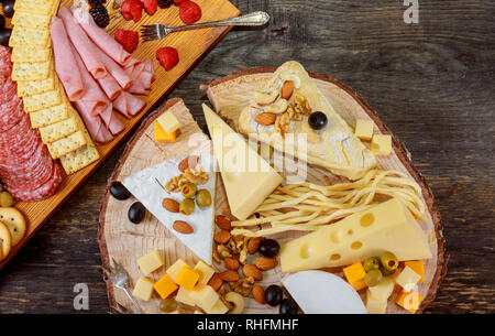 Set mit Snack verschiedene Fleisch, Käse, Cracker, grüne Oliven, Nüsse und Beeren über holztisch Hintergrund Stockfoto