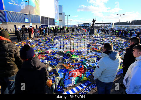 Fans schauen auf die Blumen und Schals außerhalb Cardiff City Stadium in Hommage an Emiliano Sala platziert in der Premier League Match in Cardiff City Stadium. Stockfoto