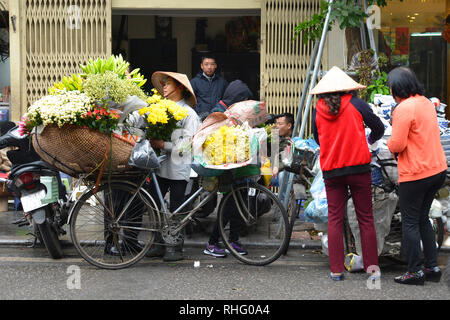 Hanoi, Vietnam - 13. Dezember 2017. Eine Straße Verkäufer verkauft frische Blumen aus der Rückseite des Ihr Fahrrad in der historischen Altstadt von Hanoi Stockfoto