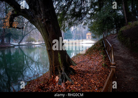 Wenig neoklassischen Gebäude reflektiert auf einem zugefrorenen See umgeben von schneebedeckten, Park von Monza, Italien Stockfoto