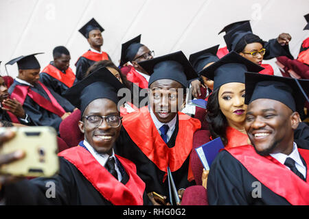 GRODNO, Weißrussland - Juni, 2018: Ausländische afrikanischen Studierenden in eckigen akademische Graduierung Kappen und schwarze Regenmäntel während der Beginn mit diploms Stockfoto