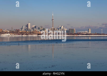 Panoramablick auf die kanadischen Winter Landschaft in der Nähe von Toronto, schöne gefrorene Ontario See bei Sonnenuntergang. Landschaft mit Winter Bäume, Wasser und blauer Himmel. Stockfoto