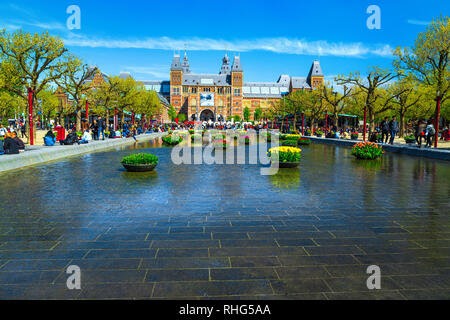 AMSTERDAM, NIEDERLANDE, 30. APRIL 2017: Staatliche Museen (Rijksmuseum) Fassade, kleinen Teich mit bunten Tulpen und IAMSTERDAM Worte eingerichtet si Stockfoto