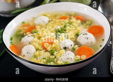 Italienische meatball Soup und Stelline glutenfreie Pasta in der Schüssel auf Schwarz. Diätetische Suppe. Baby Menü. Leckeres Essen. Stockfoto