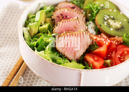 Salat. Poke Schüssel. Buddha Schüssel. Traditionelle Salat mit Stücken von medium-Rare gegrillten Ahi-Thunfisch und Sesam mit frischem Gemüse und Reis auf einen Teller. Top Stockfoto