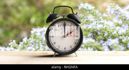 Europäische Sommerzeit Ende. Wecker auf hölzernen Schreibtisch, blur Frühling Natur Hintergrund, kopieren. 3D-Darstellung Stockfoto