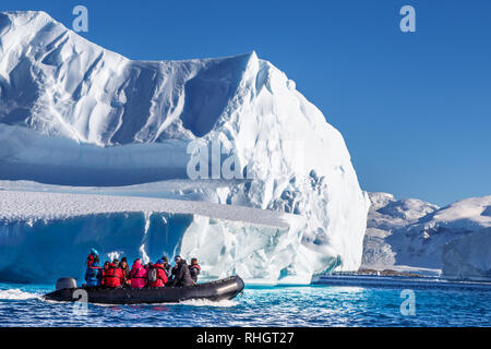 Touristen sitzen auf Zodiac Boot, erkunden riesige Eisberge in der Bucht in der Nähe von Cuverville Insel driften, Antarktische Halbinsel Stockfoto