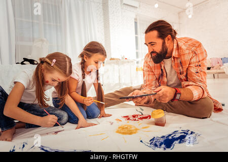 Schöne bärtige Mann seine Mädchen helfen zu malen Stockfoto