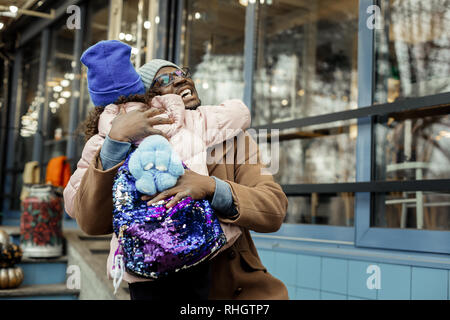 Strahlende glückliche Vater seine süße kleine Mädchen mit Rucksack umarmen Stockfoto