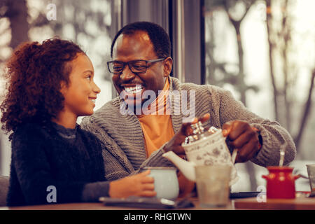 Lockigen dunkelhaarigen Tochter bei ihren liebevollen fürsorglichen Vaters Stockfoto