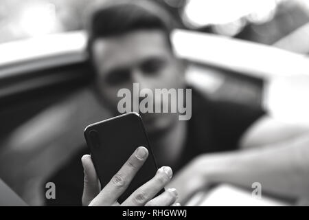 Passagier Geschäftsmann mit einem Smartphone auf dem Rücksitz des Autos. Stockfoto