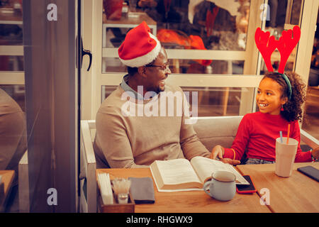 Curly girl tragen schöne Weihnachten Zubehör bei Vater auf der Suche Stockfoto