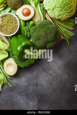 Sortiert grün getönten roh Bio Gemüse auf dunklem Hintergrund. Avocado, Kohl, Brokkoli, Blumenkohl und Bohnen Gurken mit getrimmt. Stockfoto