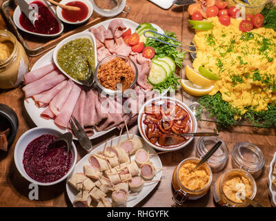 Skandinavische Büfett mit einer Auswahl an Aufschnitt, Hering, Saucen und Rührei. Stockfoto