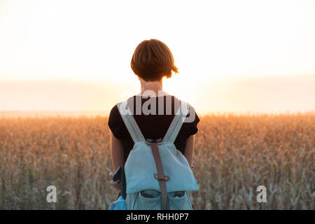 Hintergrundbeleuchtung Abbildung einer Frau Helle Sonnenuntergang genießen. Weibliche Person, die in der Abendsonne in ein Feld Stockfoto
