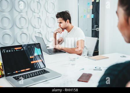 Сolleagues Analysieren digital berichtet auf dem Bildschirm überwachen und Erstellung der finanziellen Report für Investoren. Team von Business Manager bei Mann und Frau sitzen Stockfoto