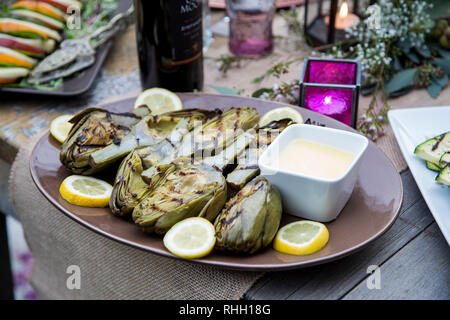 Servierplatte von gegrillten Artischocken mit Dip auf im Hinterhof Dinner Party Tabelle. Stockfoto