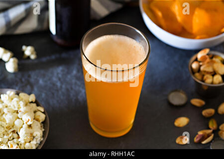 Pint Glas Handwerk Weißbier auf schiefer bar Oberfläche mit Verschlusskappen und Pistazien. Stockfoto