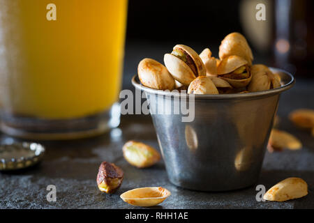 Kleine Tasse mit Pistazien auf Theke mit pint Glas Handwerk Weißbier. Stockfoto