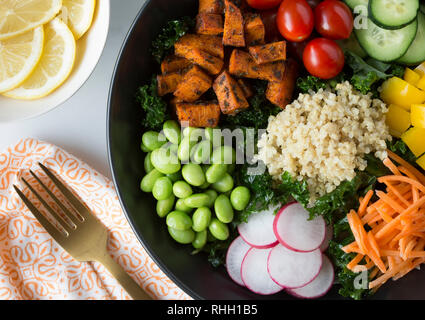 Luftaufnahme von gesunden kale Salatschüssel mit Gemüse - Süßkartoffeln, Tomaten, Gurken, Paprika, Karotten, Rettich, und Edamame mit Quinoa. Stockfoto