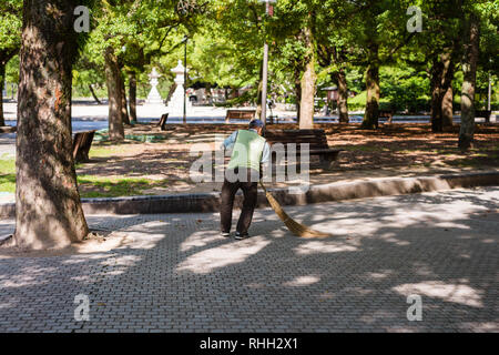 Und der alte Mann im Park fegen. Bleiben aktiv im Ruhestand ist eines der Geheimnisse von Japans lange Lebensdauer Stockfoto