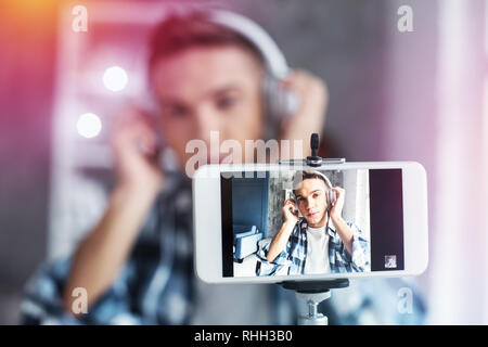 Junger Mann mit squared Shirt, Foto in seinem Wohnzimmer sitzen Stockfoto