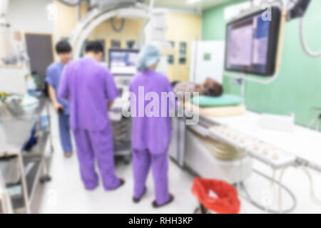 Blur ist der Arzt die Durchführung einer Patientenuntersuchung in der digitalen Subtraktionsangiographie Zimmer, DSA-Labor, Op mit X-ray medizinischen Scan. Stockfoto