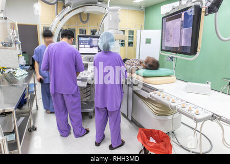 Der Arzt ist die Durchführung einer Patientenuntersuchung in der digitalen Subtraktionsangiographie Zimmer, DSA-Labor, Op mit X-ray medizinischen Scan. Stockfoto