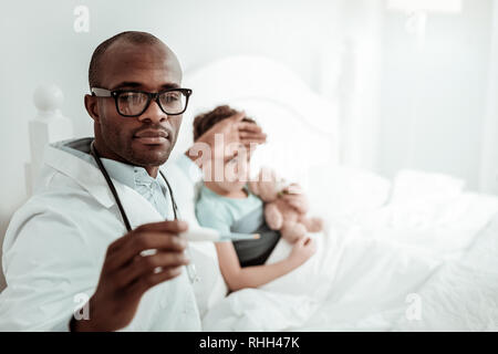 Nahaufnahme von ernsten medizinischen Arbeiter, der Kontrolle der Temperatur Stockfoto