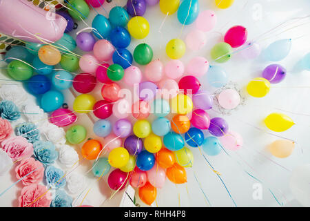 Gruppe von bunten Heliumballons auf einer weißen Decke stecken. Multi-farbiges Papier Blumen an der Wand. Hochzeit Dekor. Stockfoto