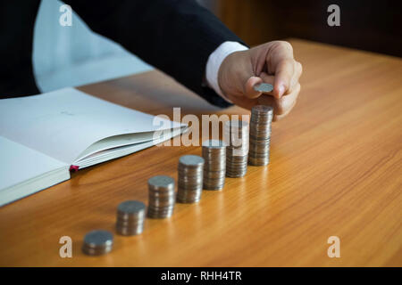 Geschäftsmann nimmt Münzen auf den Tisch und zählt Geld. Geschäftskonzept. Stockfoto