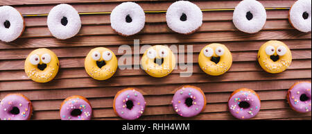 Lecker donuts hängt über Holz- Paravent. Weiß Gelb und Weiß beschichtet. Glasur. Stockfoto